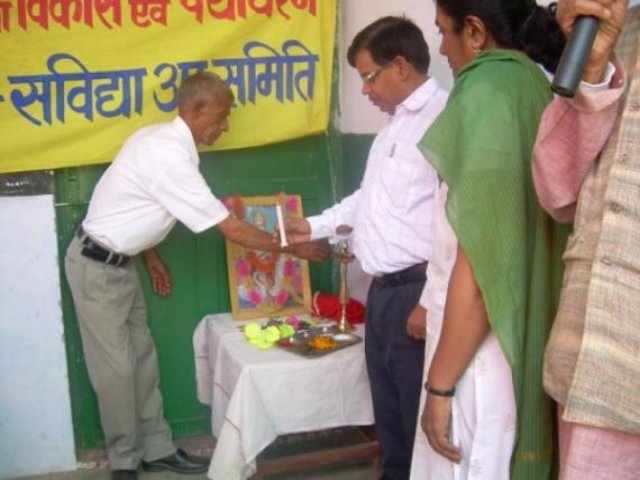 A presentation beneath the Savidya Samiti banner, with items set out on the table.