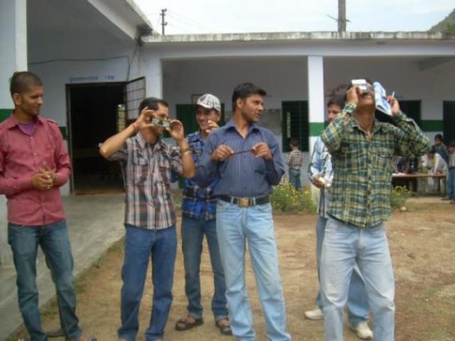 Men trying out hand-held optical instruments during a demonstration.