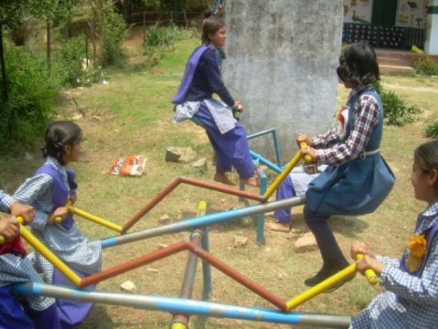 Girls riding the roundabout in the school playground.
