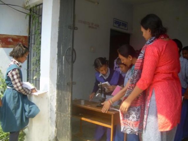 A teacher working with children at a table by the window.