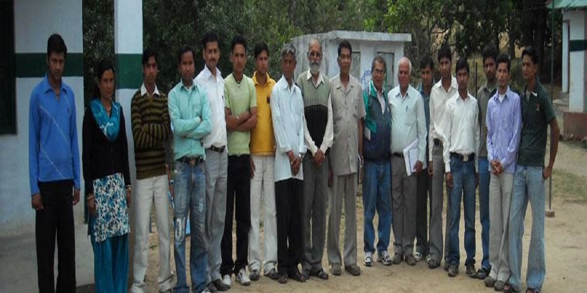 A long line of villagers and volunteers standing together for a photograph outside the building.