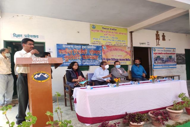 A speaker at the lectern, guests seated at the table behind.