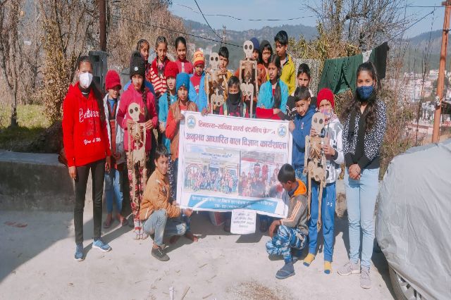 Volunteers and children holding a programme banner.