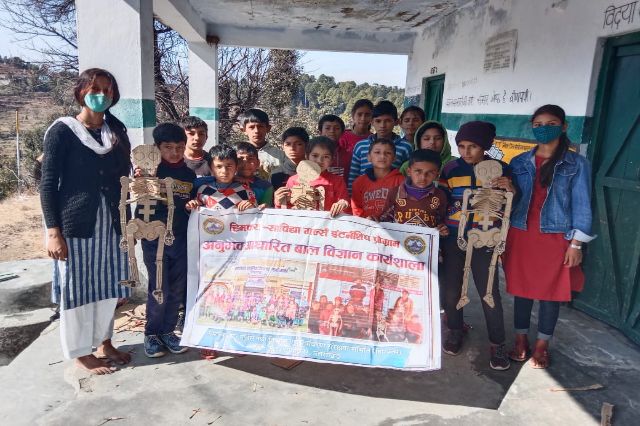 Children and volunteers holding the programme poster in the school yard.