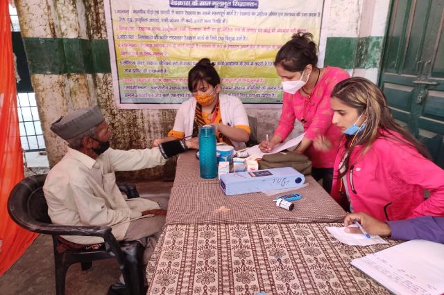 A health worker recording details at a table during a village camp.