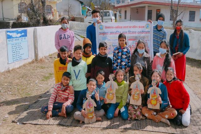 Children outside the school with the paper figures they had made.