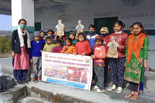 Children and volunteers holding an awareness poster outside the school.