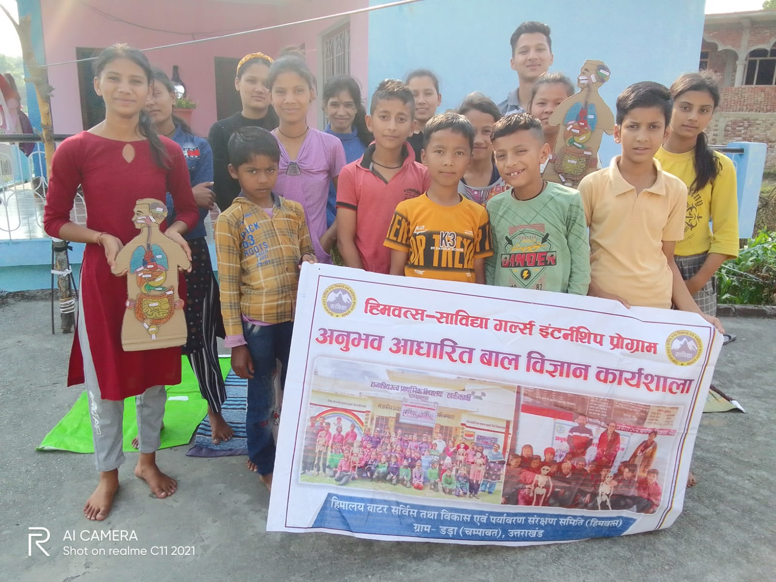 Girls and children standing behind the banner for an experience-based children’s science workshop.