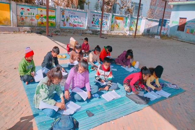 Children working through papers on the mats at a Navodaya preparation class.
