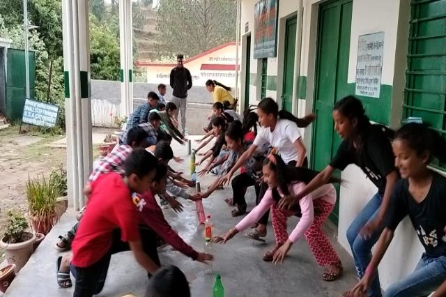 Campers crouched in a line along the veranda during a summer camp game.
