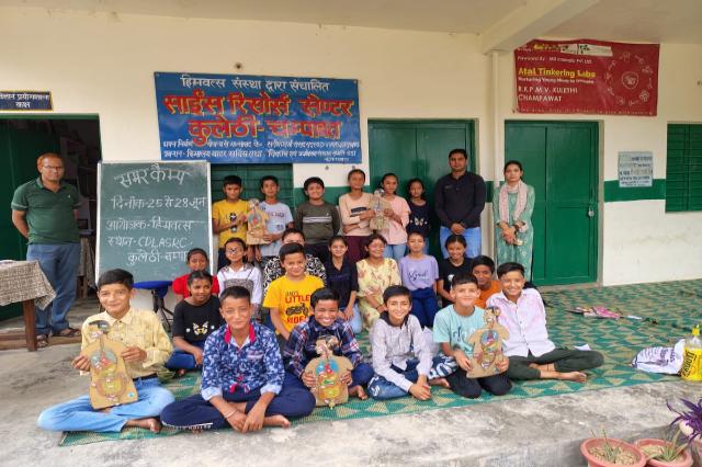 Children holding their printed sheets at the end of the human body workshop, under the programme banner.
