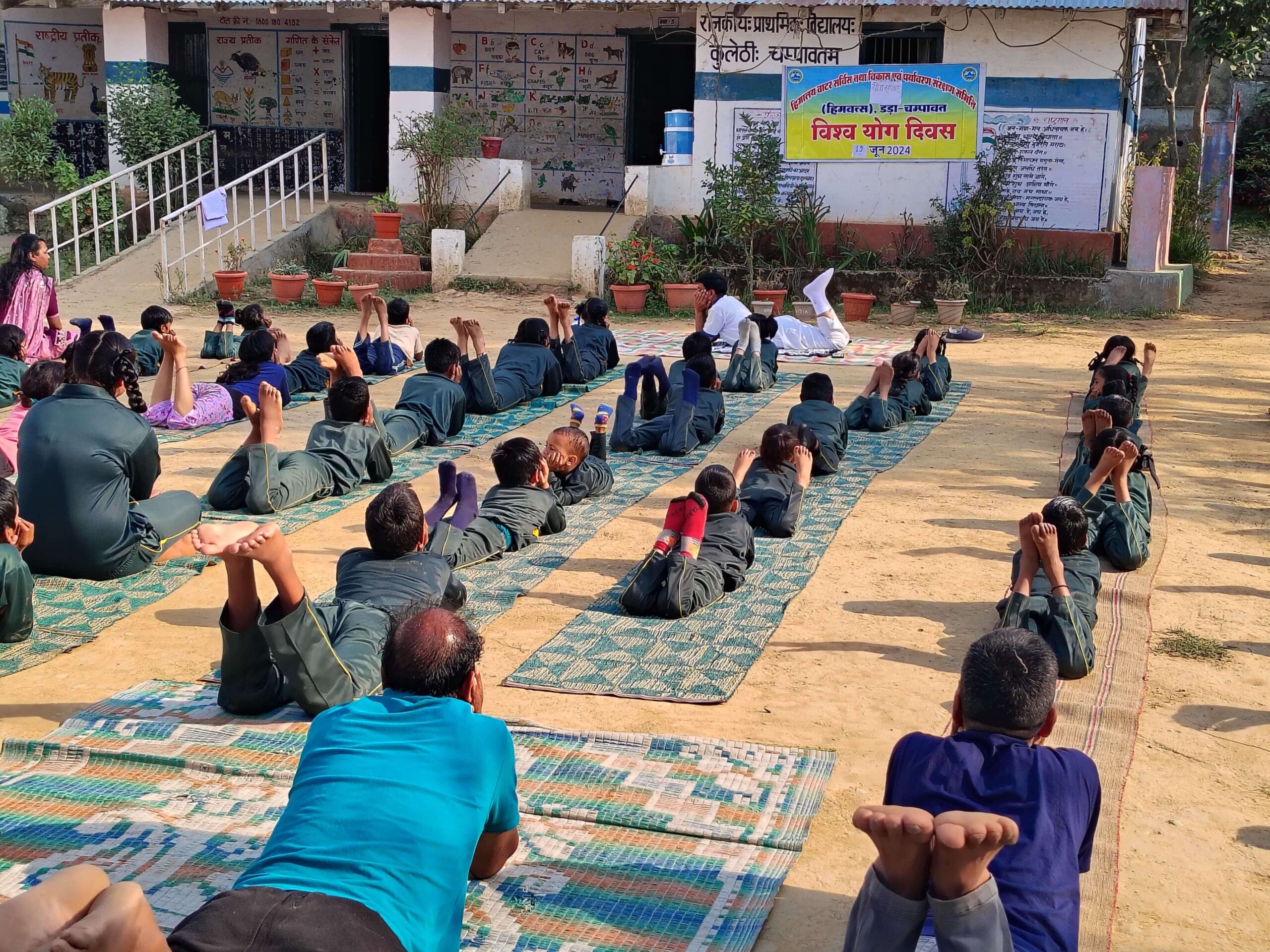 Rows of participants on mats in the open during an International Yoga Day session.