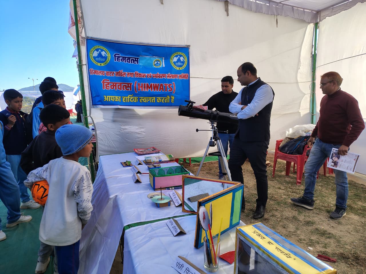A telescope being set up under the marquee, a boy watching.