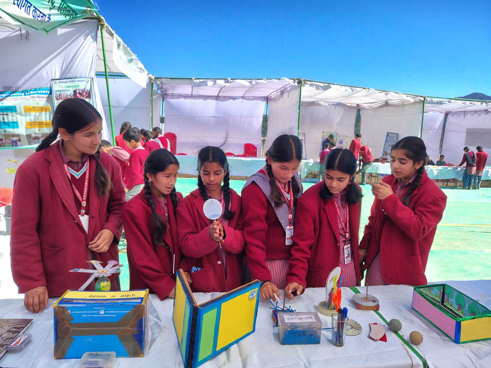 Students examining the models on the table, one of them using a magnifier.