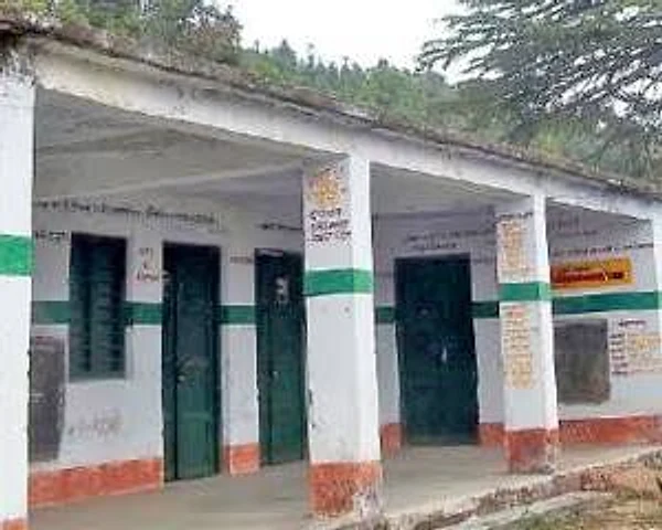 The single-storey government primary school at Champawat, its verandah pillars and doors painted green and white, with Hindi signage along the wall.