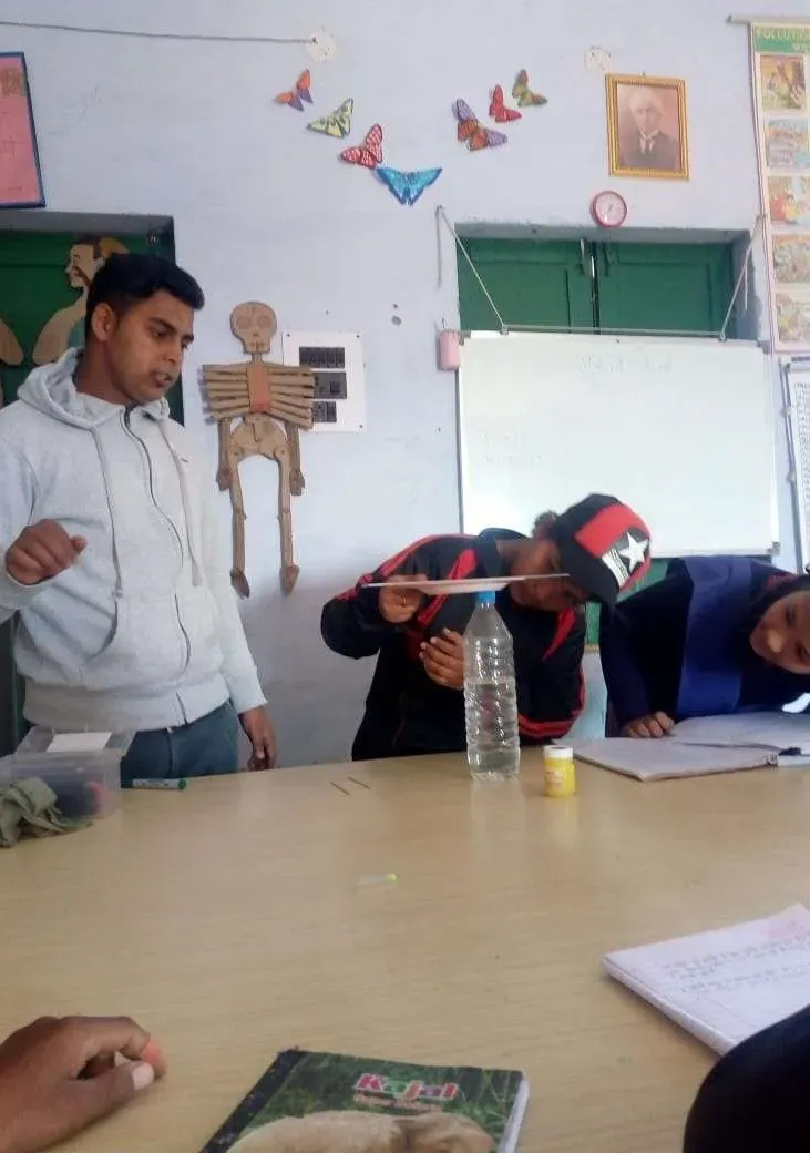 Students carrying out an experiment at a desk, an anatomical chart on the wall behind them.