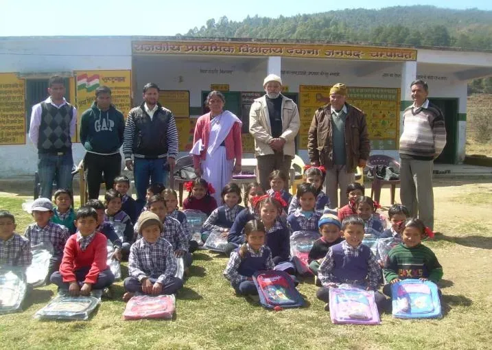 School bags being handed out to children in a school courtyard.